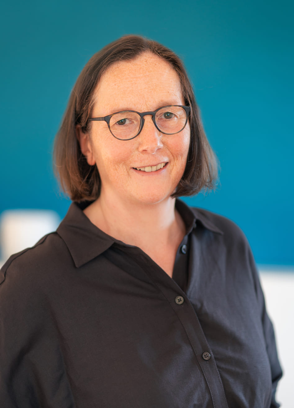 Porträt von Dr. med. Annette Barwe vor petrolblauer Wand