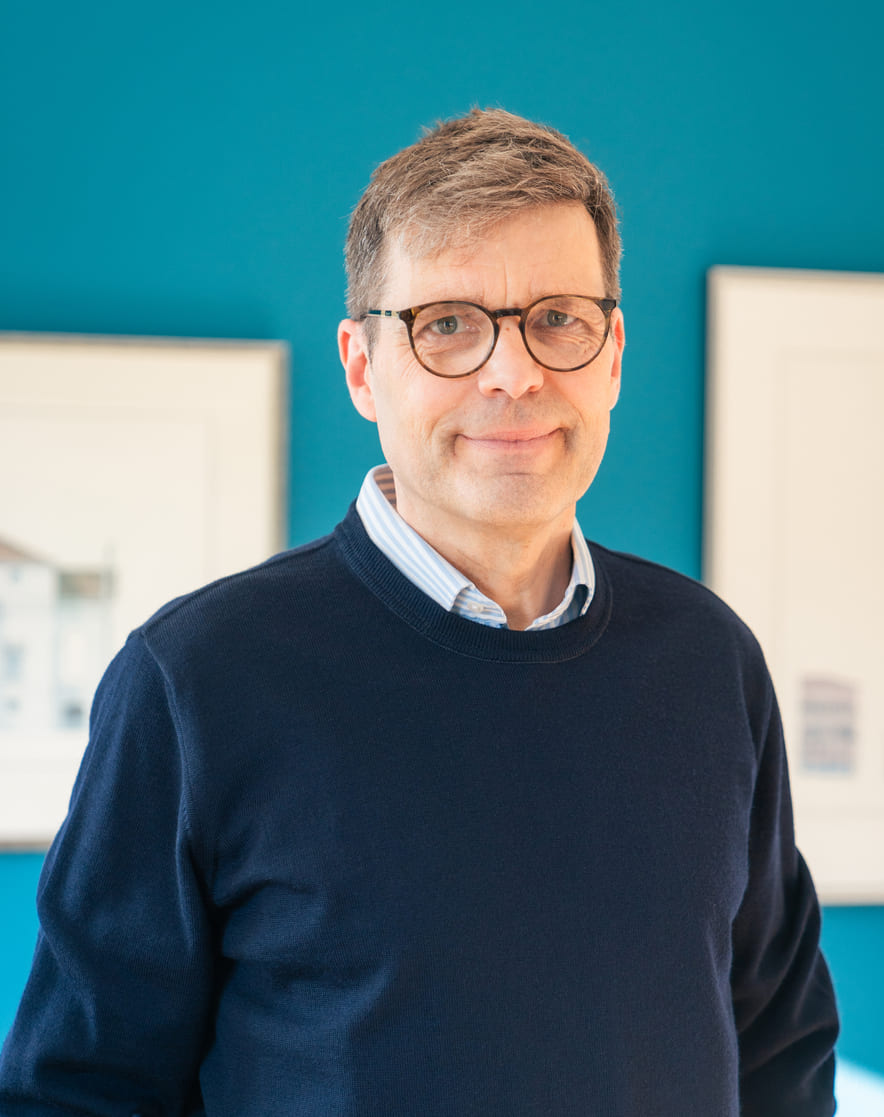 Porträt von Dr. med. Georg Driesch vor petrolblauer Wand